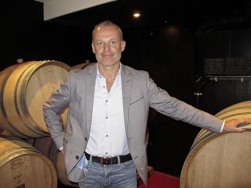 Jean-Luc Kursner dans une cave, entre des barriques
